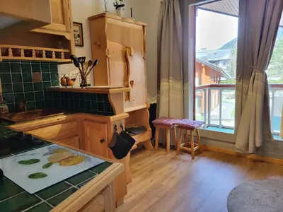 a kitchen with wooden cabinets and a large window at Studio Mezzanine Les Combettes E in Les Contamines-Montjoie