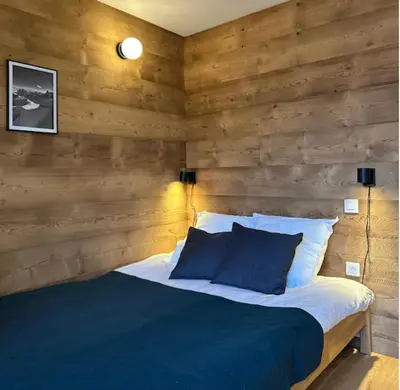 a bedroom with a wooden wall with a bed at Charming Mont-Blanc View Studio in Chamonix in Chamonix-Mont-Blanc