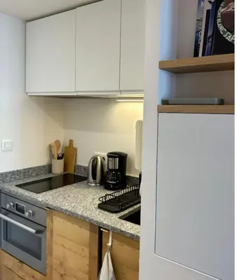 a kitchen with white cabinets and a stove top oven at Charming Mont-Blanc View Studio in Chamonix in Chamonix-Mont-Blanc