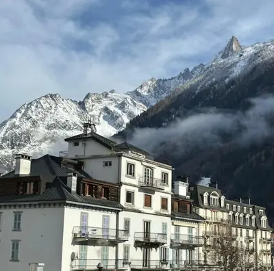 a large white building with mountains in the background at Charming Mont-Blanc View Studio in Chamonix in Chamonix-Mont-Blanc