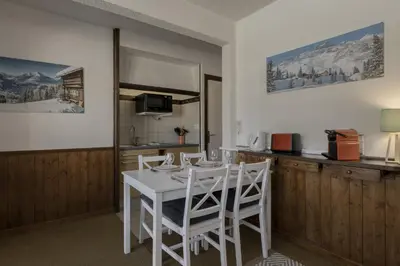 a kitchen with a white table and white chairs at Le Miage in Chamonix-Mont-Blanc
