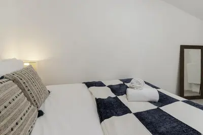 a white bed with a blue and white checkered blanket at Le Triolet - Centre-ville - Balcon avec vue in Chamonix-Mont-Blanc