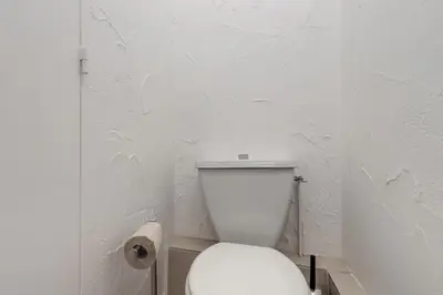 a white bathroom with a toilet and a roll of toilet paper at Le Triolet - Centre-ville - Balcon avec vue in Chamonix-Mont-Blanc