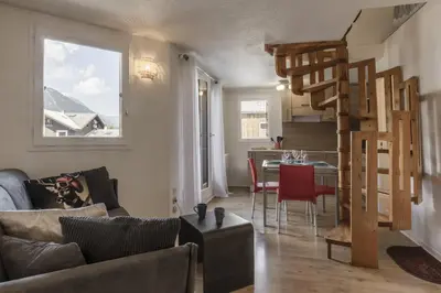 a living room with a spiral staircase and a table at Le Triolet - Centre-ville - Balcon avec vue in Chamonix-Mont-Blanc