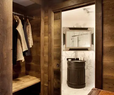 a bathroom with wooden walls and a toilet and a mirror at Chalet Alta in Chamonix-Mont-Blanc