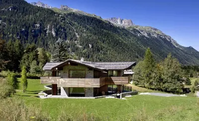 a house in a field with a mountain at Chalet Alta in Chamonix-Mont-Blanc