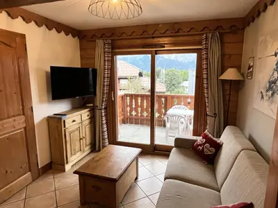 a living room with a couch and a tv and a balcony at Résidence Les Fermes du Soleil - maeva Home - Appartement 3 pièces 6 personnes - Prestige MAE-4281 in Arâches-la-Frasse