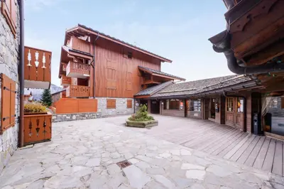 an empty courtyard of a building with wooden buildings at Résidence Les Fermes du Soleil - maeva Home - Appartement 3 pièces 6 personnes - Prestige MAE-4281 in Arâches-la-Frasse