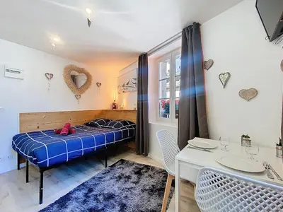 a bedroom with a blue bed and a table at Petit STUDIO STAR CHAMONIX HYPER CENTRE in Chamonix-Mont-Blanc