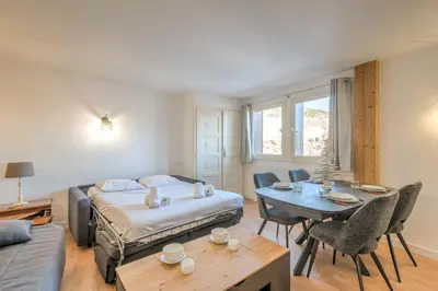 a living room with a bed and a table and chairs at Appartement Cimes Étoilées - Welkeys in Megève