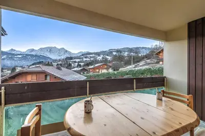 a room with a wooden table and a large window at Appartement Alpestre - Welkeys in Combloux