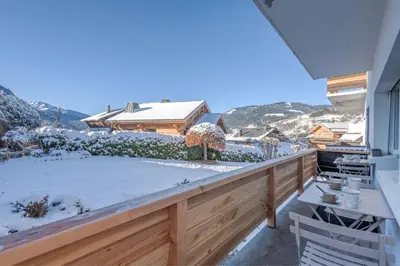 a snow covered balcony with a view of a house at Appartement Hermine - Welkeys in Megève