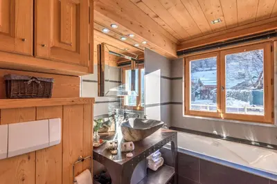 a bathroom with a sink and a tub and a window at Appartement Hermine - Welkeys in Megève