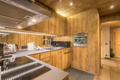 a kitchen with wooden cabinets and a stainless steel sink at Appartement Hermine - Welkeys in Megève