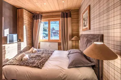 a bedroom with a bed with a lamp and a window at Appartement Hermine - Welkeys in Megève