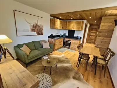 a living room with a green couch and a kitchen at Le green d'Arbois - Ski au pied in Megève