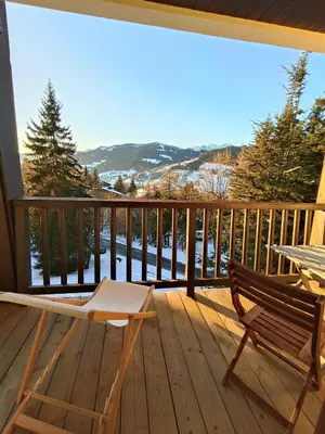 a deck with a chair and a table and a view at Le green d'Arbois - Ski au pied in Megève