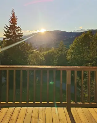 a view of the sun setting on a deck at Le green d'Arbois - Ski au pied in Megève