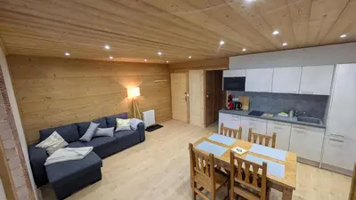 a living room with a blue couch and a kitchen at L'Helvetia in Chamonix-Mont-Blanc