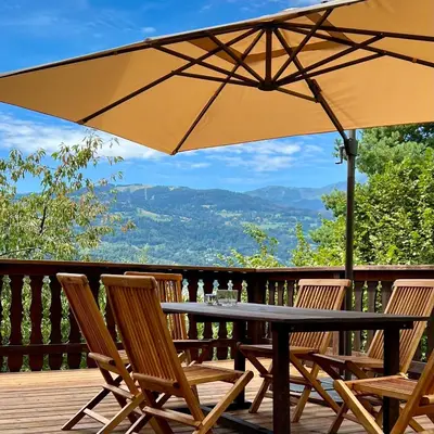a table and chairs on a deck with an umbrella at Chalet 8 personnes in Passy