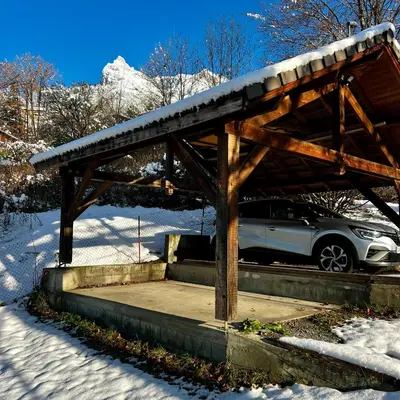 a wooden structure with a car parked in the snow at Chalet 8 personnes in Passy