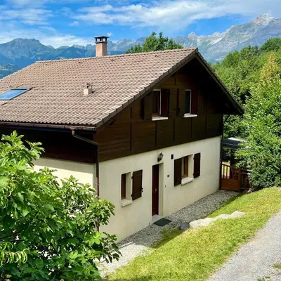 a house with a roof with mountains in the background at Chalet 8 personnes in Passy