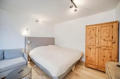 a small bedroom with a bed and a blue couch at Studio 2 personnes in Passy
