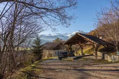 a house with a car parked under a wooden pavilion at Studio 2 personnes in Passy