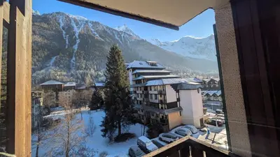 a view from the balcony of a hotel with snow covered mountains at L'Oursina in Chamonix-Mont-Blanc