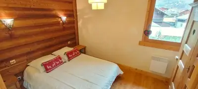 a bedroom with a bed with a wooden wall at 3 chambres - 2 SDB - 7 personnes - 100 m télécabine GME in Samoëns