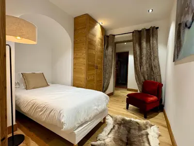 a bedroom with a bed and a red chair at Woodpecker Appartement au coeur du village in Les Houches