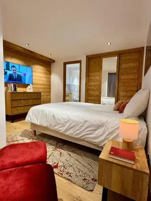 a bedroom with a large bed and a flat screen tv at Woodpecker Appartement au coeur du village in Les Houches
