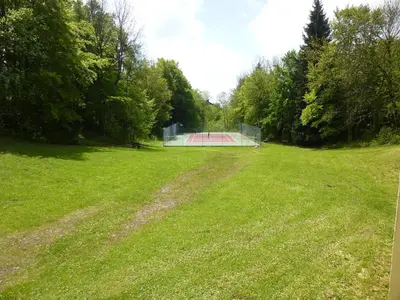 a green field with a tennis court in the distance at Joli studio aux Carroz d'Arâches in Arâches-la-Frasse