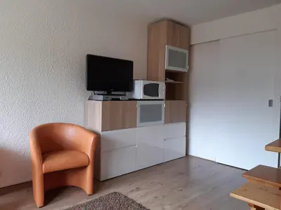 a living room with a tv and a chair at Joli studio aux Carroz d'Arâches in Arâches-la-Frasse