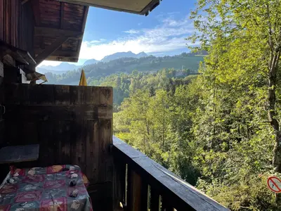 a room with a bed on a balcony with a view at Grand studio Combloux - Vue Mont Blanc in Combloux