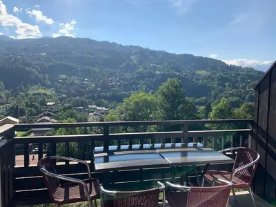 a table and chairs on a balcony with a view at Les fermes de saint gervais in Saint-Gervais-les-Bains