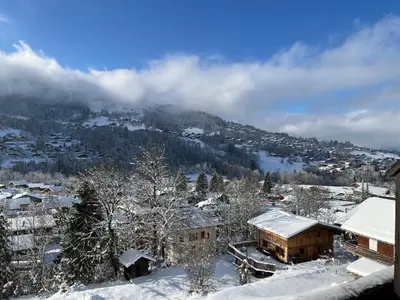 a town covered in snow with a mountain in the background at Les fermes de saint gervais in Saint-Gervais-les-Bains