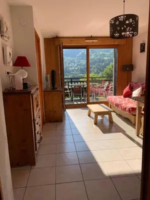 a living room with a large window and a table at Les fermes de saint gervais in Saint-Gervais-les-Bains
