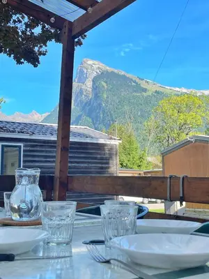 a table with glasses on a table with a mountain in the background at Le Refuge, Mobil Home 3 rooms avec Climatisation in Samoëns