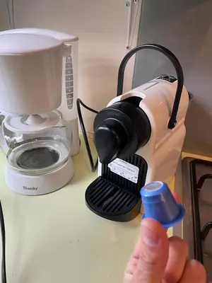 a person holding a drink in front of a coffee maker at Le Refuge, Mobil Home 3 rooms avec Climatisation in Samoëns