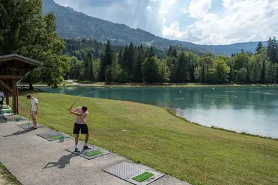 two people playing a game of golf by a lake at Le Refuge, Mobil Home 3 rooms avec Climatisation in Samoëns