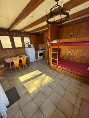 a room with a bunk bed and a table and a kitchen at Charmant petit chalet cosy in Combloux