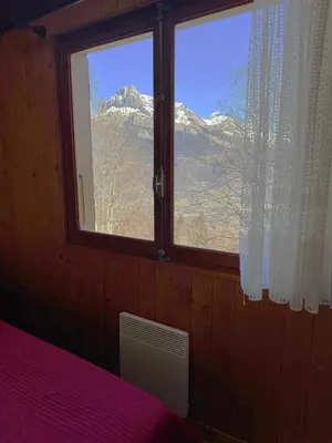 a bedroom with a window with a mountain view at Charmant petit chalet cosy in Combloux