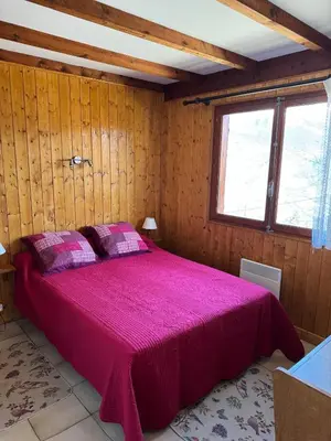 a bedroom with a large bed with a pink blanket at Charmant petit chalet cosy in Combloux