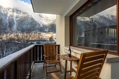 a balcony with two chairs and a table and a window at Les Trois Balcons Apartment - Chamonix All Year in Chamonix-Mont-Blanc