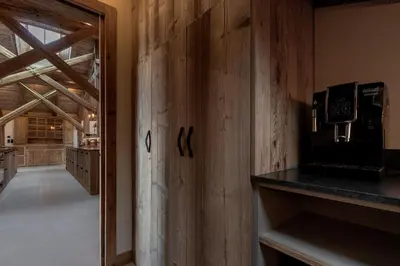 a kitchen with a wooden wall with a stove at Ferme des Choseaux - Grand Confort et ski in Combloux