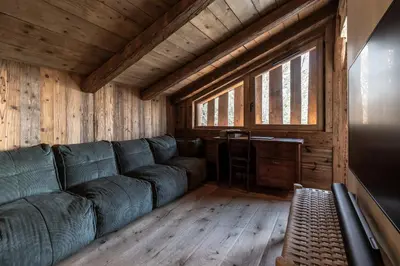 a living room with a green couch in a wooden room at Ferme des Choseaux - Grand Confort et ski in Combloux