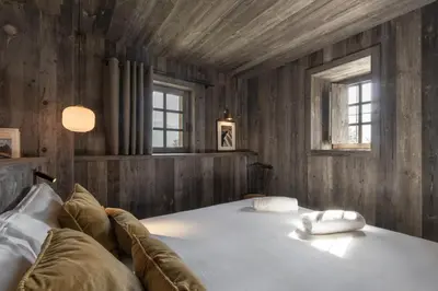 a bedroom with a large bed with wooden walls and windows at Ferme des Choseaux - Grand Confort et ski in Combloux