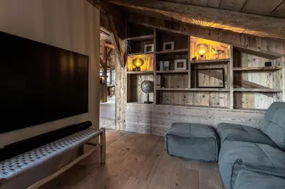 a living room with a couch and a flat screen tv at Ferme des Choseaux - Grand Confort et ski in Combloux