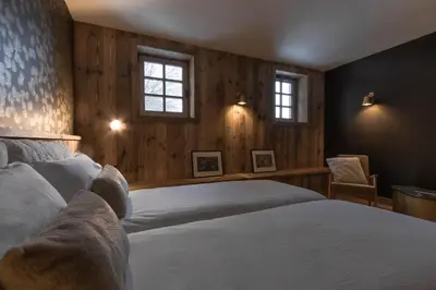 a bedroom with a bed and two windows at Ferme des Choseaux - Grand Confort et ski in Combloux